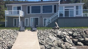 A two-story house with a balcony, a concrete pathway, and a rocky garden area. - Sunset Retreat Awaits (Big Pond)