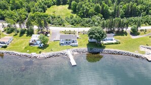An aerial view of a lakeside property with multiple houses, a dock, and a stone wall. - Sunset Retreat Awaits (Big Pond)