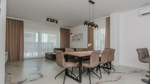 A modern dining area with a marble floor, a wooden table, and matching chairs. - Luxurious home in Vrsi (Vrsi)