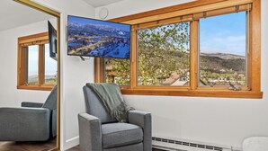 A modern living room with a large window, a flat-screen TV, and a grey armchair. - Mountain modern-At the base (Steamboat Springs)