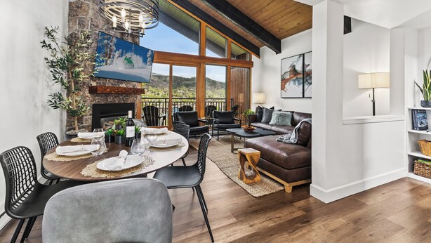 A spacious living area with a fireplace, dining table set for four, and a comfortable seating area with a sofa and chairs. - Mountain modern-At the base (Steamboat Springs)