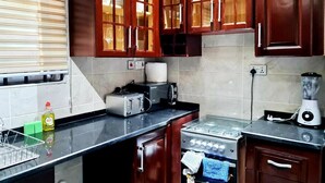 Una cocina con armarios de madera, estufa, tostadora y licuadora.