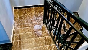 Una escalera con baldosas de mármol y barandilla de metal negro.