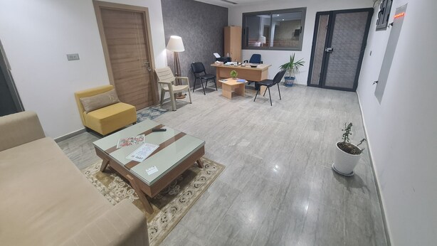 A modern living room with a sofa, coffee table, and a desk with a computer.