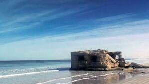 A coastal scene with a stone structure by the sea.
