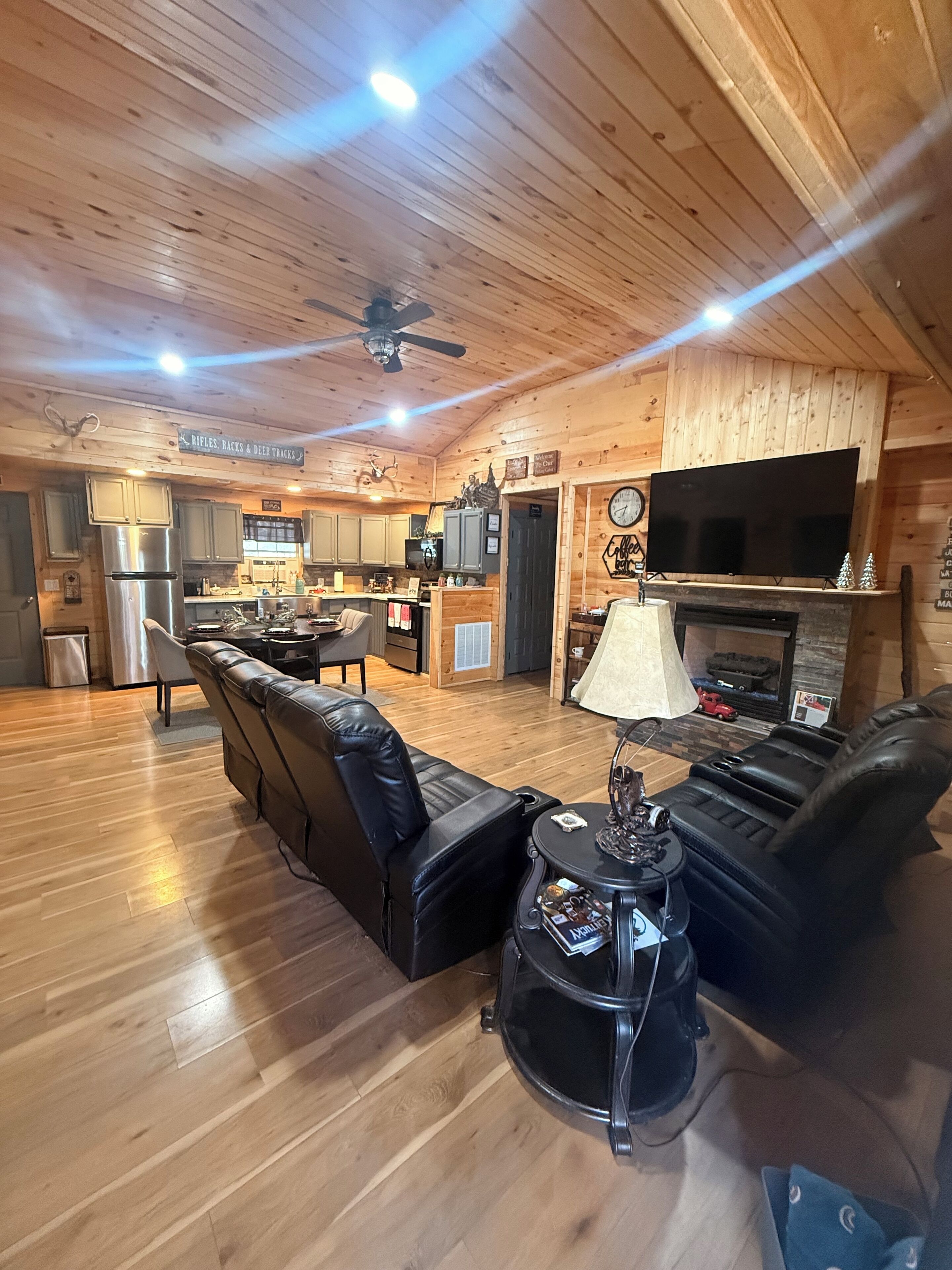 A spacious living room with a fireplace, leather sofas, a coffee table, and a television.