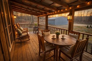 A wooden deck with a round table and chairs, a small table with a plant, and a lantern. - Charming cabin retreat: cozy, scenic, and perfect for a relaxing getaway! (London)