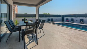 A covered outdoor area with a pool, a table with chairs, and a view of the surrounding buildings. - Beach front home in Vrsi (Vrsi)