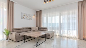 A modern living room with a sectional sofa, a coffee table, and a large window with sheer curtains. - Beach front home in Vrsi (Vrsi)