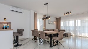 A modern dining area with a marble floor, a central table with chairs, a sofa, and a pendant light fixture. - Beach front home in Vrsi (Vrsi)