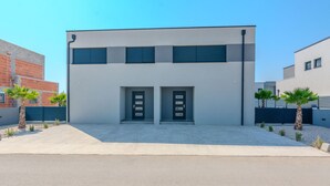 A modern building with two symmetrical doors, a flat roof, and a concrete driveway. - Beach front home in Vrsi (Vrsi)