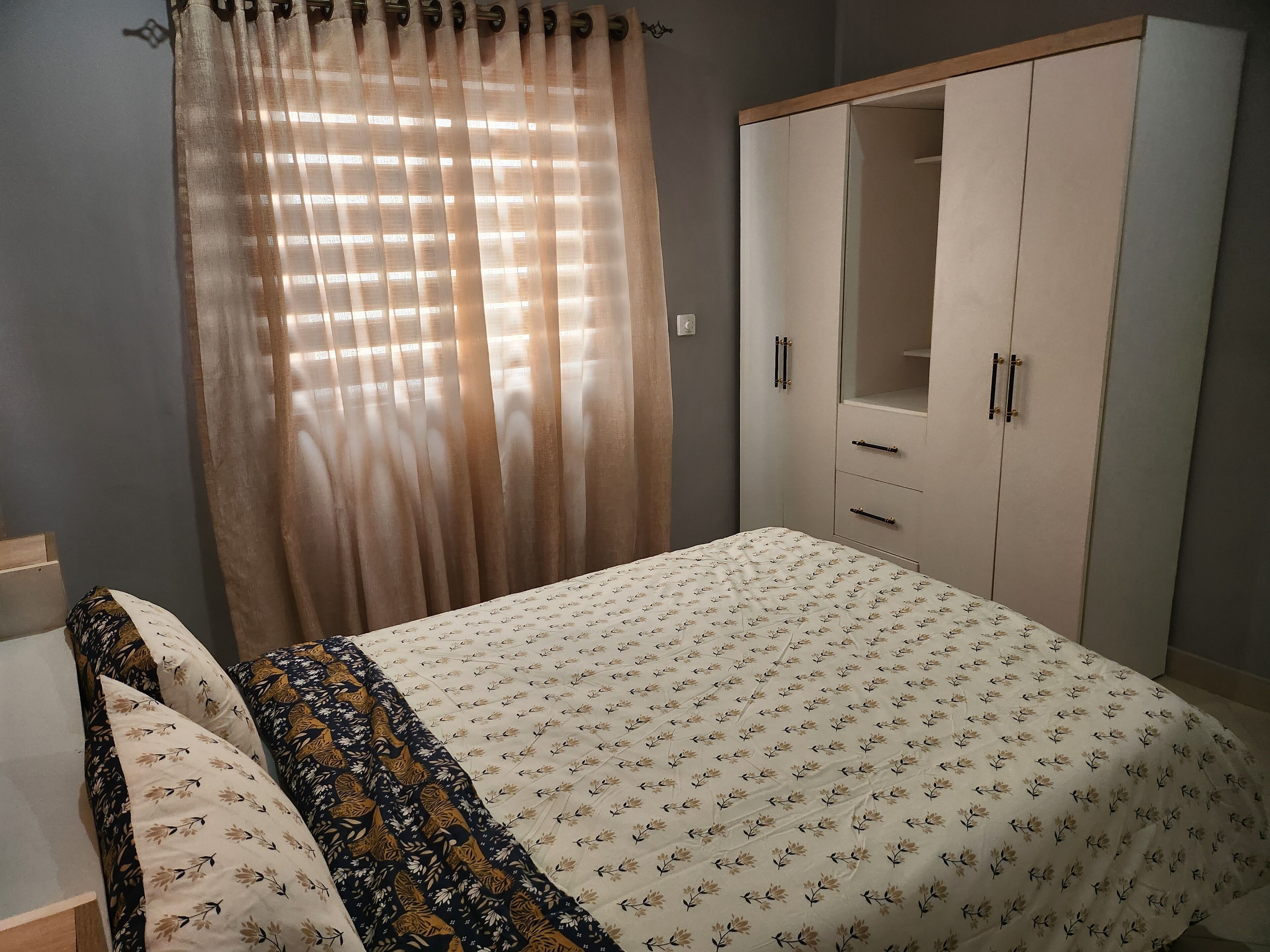 Une chambre à coucher avec un lit, une armoire et une fenêtre avec des rideaux.