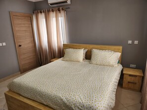 A bedroom with a wooden bed, two bedside tables, a wooden wardrobe, and a window with curtains. - Spacious Luxury 3Bed Hse in Tema Netflix (Tema)
