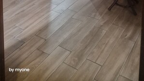Een kamer met houten vloer, een kapstok en een stoel op de achtergrond.