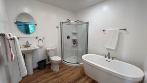A modern bathroom with a glass shower enclosure, a freestanding bathtub, a sink, and a toilet.