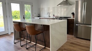 A modern kitchen with a large island, stainless steel appliances, and a view to the outdoors.