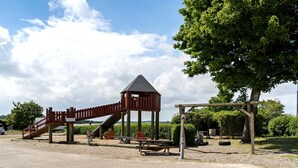 Une aire de jeux avec un toboggan, une structure d’escalade et un petit pavillon.