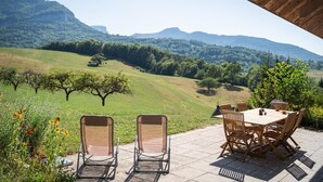 An outdoor patio with a table and chairs, overlooking a hilly landscape with trees and a clear sky. - Apartment 'Le Chalet De La Source' with Mountain View, Private Terrace and Wi-Fi (Montagnole)