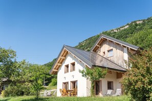 Ett tvåvåningshus med ett sluttande tak, träfasad och en liten balkong.