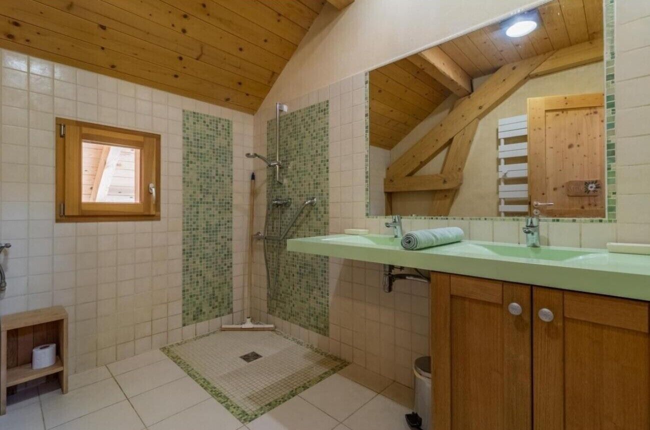 Un baño con ducha, lavamanos, espejo y ventana.
