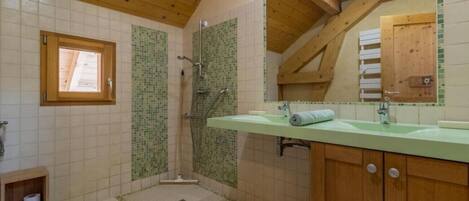 Un baño con ducha, lavamanos, espejo y ventana.