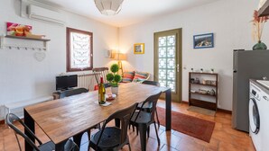 Un coin repas avec une table en bois, des chaises, un téléviseur et une lampe.