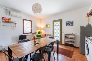 Een eethoek met een houten tafel, stoelen, een televisie en een lamp.
