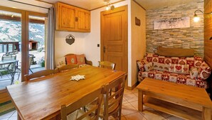 A wooden dining table with chairs, a wooden bench, a cushioned sofa, and a stone-patterned wall.