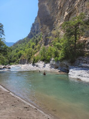 A river with clear water, surrounded by rocky cliffs and greenery.