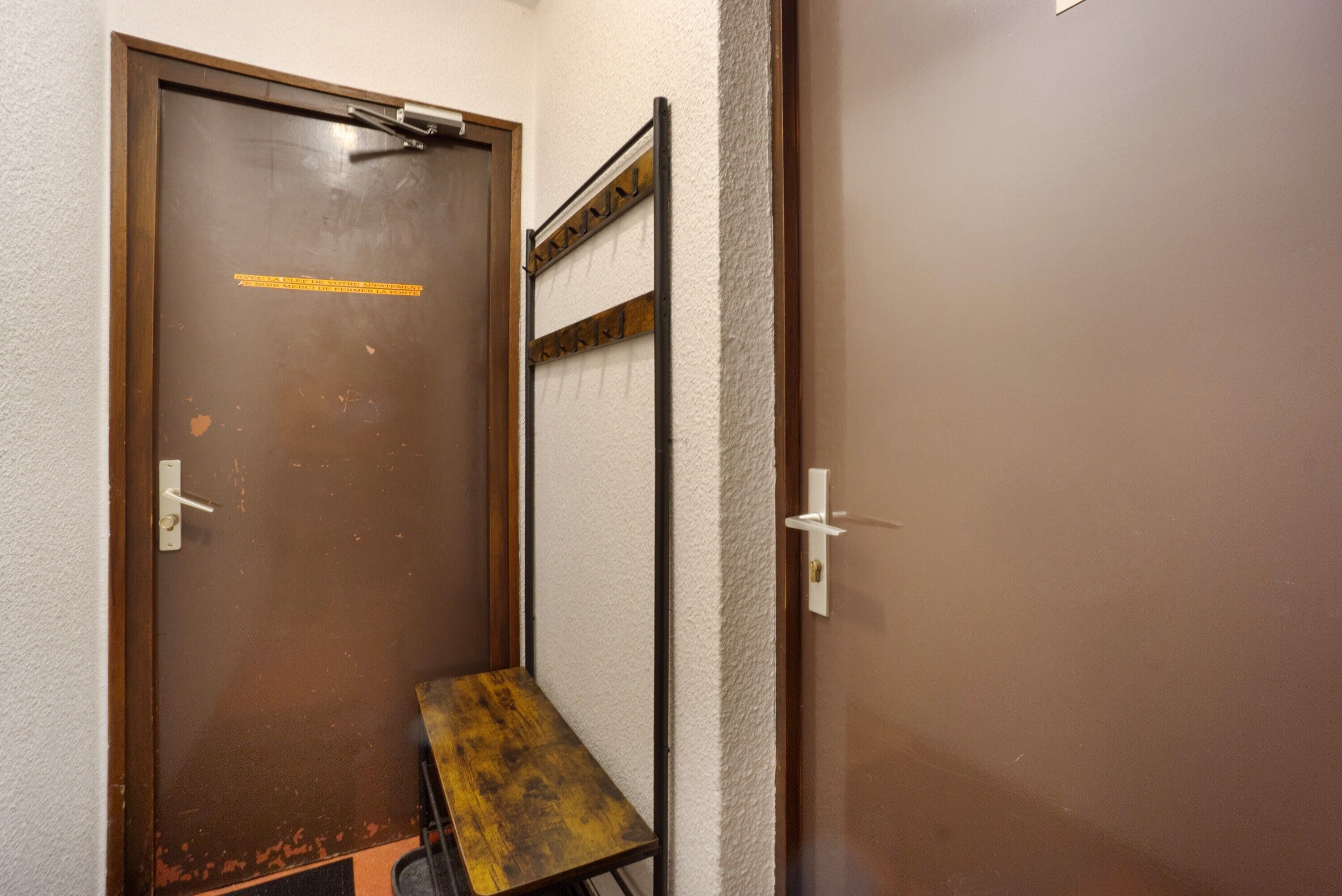 A door with a metal handle, a small bench, and a metal rack against the wall.