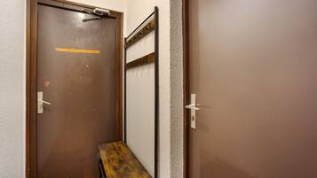 A door with a metal handle, a small bench, and a metal rack against the wall.