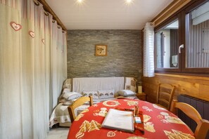 Ein gemütliches Zimmer mit einem Bett, einem Esstisch mit roter Tischdecke und einer Steinwand.