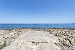Eine felsige Küstenlinie mit freiem Blick auf das Meer und das entfernte Land.