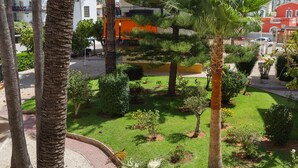 A courtyard with palm trees, a small garden, and a building with balconies.