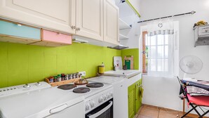 Une cuisine avec un four blanc, des placards verts et une fenêtre avec un rideau.