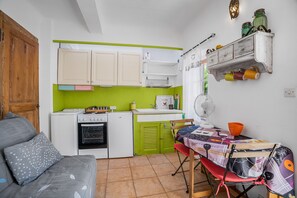 A compact kitchen with a dining area, a wooden door, and a small oven.