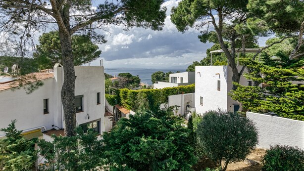 A coastal residential area with white buildings, trees, and a view of the sea. - Holiday Home 'Amparo' with Sea Views, Private Pool and Wi-Fi (L'ESCALA)