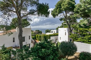 A coastal residential area with white buildings, trees, and a view of the sea. - Holiday Home 'Amparo' with Sea Views, Private Pool and Wi-Fi (L'ESCALA)