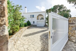 A white house with a stone pathway leading to a gated entrance.