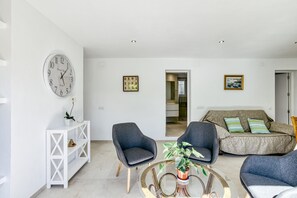 A modern living room with a white console table, two armchairs, a round coffee table, and a sofa with striped cushions.