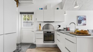 A modern kitchen with white cabinetry, a built-in oven, a coffee machine, and a wooden countertop with bread and fruit. - Lovely home in Esbjerg V with WiFi (Esbjerg V)