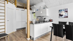 A modern kitchen with white cabinets, a wooden staircase, and a dining area with black chairs. - Lovely home in Esbjerg V with WiFi (Esbjerg V)