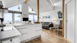 A modern kitchen with a large island, a dining area with a grey sofa, and a view of the sea. - Lovely home in Esbjerg V with WiFi (Esbjerg V)