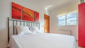 Un dormitorio con una cama, una ventana con vistas y una puerta.