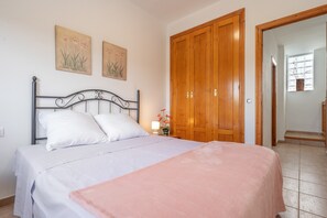 Une chambre à coucher avec un lit, une armoire en bois et un tableau accroché au mur.