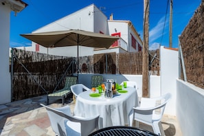 A patio with a round table, white chairs, a grill, and a table umbrella. - Apartment 'Apartamento Imperial' with Wi-Fi and Air Conditioning (Colònia de Sant Jordi)