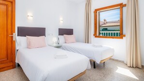 Een hotelkamer met twee bedden, een raam met gordijnen en uitzicht op een gebouw.