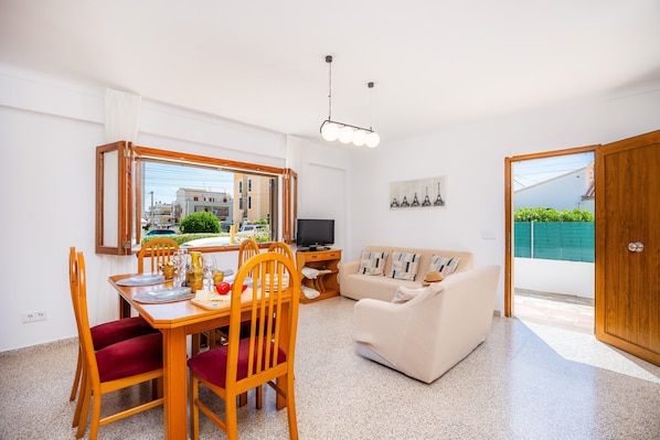 A living room with a dining area, a television, and a view of the outside.