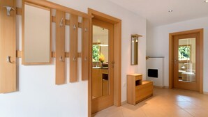 A modern interior with wooden doors, a mirror, a small wooden bench, and a tiled floor.
