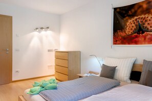 Ein Schlafzimmer mit Bett, Kleiderschrank, Schreibtisch und Wandteppich.
